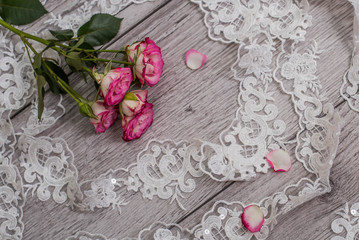 White wooden background with white spring flowers roses and lace ribbon. Happy womans day. The texture of lace on wooden background.