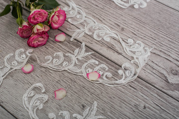 White wooden background with white spring flowers roses and lace ribbon. Happy womans day. The texture of lace on wooden background.