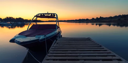 Fototapeten Boat near a pier at sunrise © bogdanvija