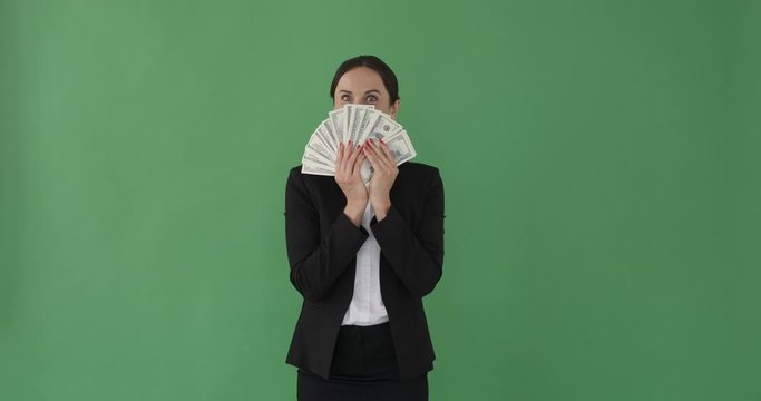 Happy businesswoman smelling cash dollars over green background