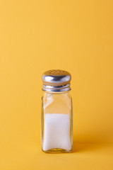 Glass salt shaker on yellow background