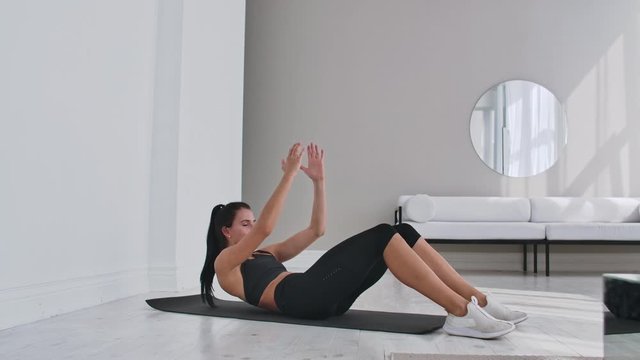 Home fitness concept. Woman doing abs crunches on floor at home, copy space.