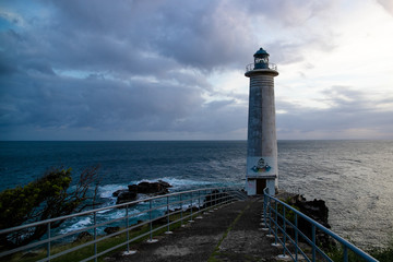 Naklejka premium Phare en bord de mer agitée, fin de journée nuageuse