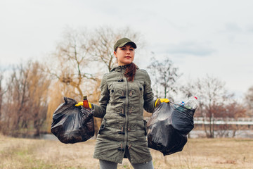 Litter picking. Woman volunteer cleaning up the trash in park. Picking up garbage outdoors. Ecology...