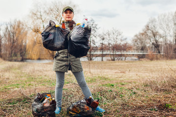 Litter picking. Woman volunteer cleaning up the trash in park. Picking up garbage outdoors. Ecology...