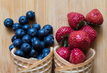 Two waffle cones for ice cream with blueberries and strawberries. Close-up. The concept of organic healthy eating. Detox diet. Summer concept. Top view.