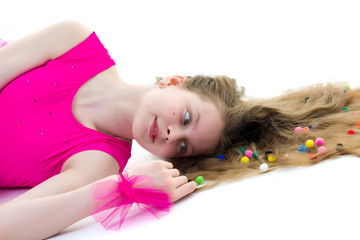 Obraz na płótnie Canvas A cute girl gymnast of school age is lying on the floor with lon