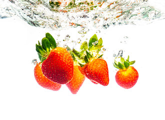 Strawberries falling into water causing bubbles all around it. Healthy food concept