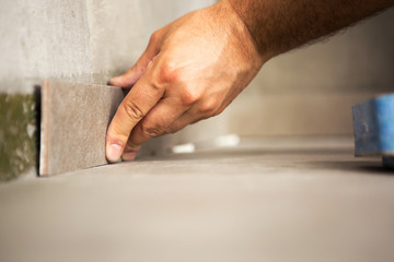 Fototapeta na wymiar Hand of construction master gluing ceramic tile to wall.