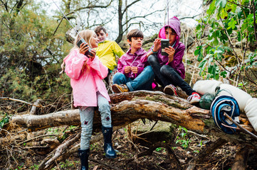 Young friends children using a walkie-talkie standing on the forest