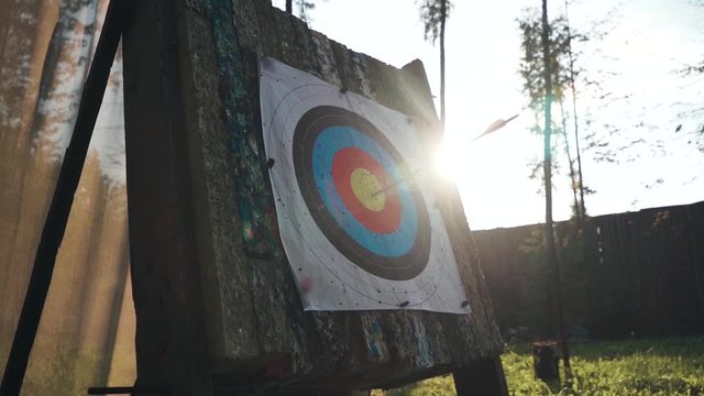 Nicw cinematic view of target for archery with sun on the background and bow arrow hit the target in center.