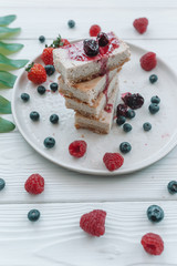 Slice of classic cheesecake with fresh berries on the white plate - healthy organic summer dessert.