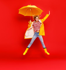 young happy emotional cheerful girl laughing and jumping with yellow umbrella   on colored red...