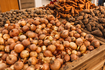 Baskets of onions, potatoes and carrots on the store counter. Vegetable on display in the supermarket