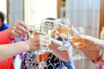 Cheers. Group of people drinking and toasting in restaurant. Hands holding glasses of champagne and wine making toast. Christmas new year wedding holiday party time. Celebration and nightlife concept
