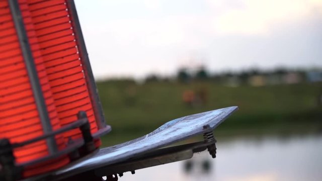 Slow motion view of throwing machine for clay pigeon shooting with orange plates near water