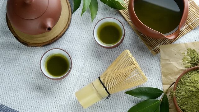 Green tea powder with leaf in ceramic dish on the table, Japanese wire whisk made of bamboo for matcha tea ceremony.