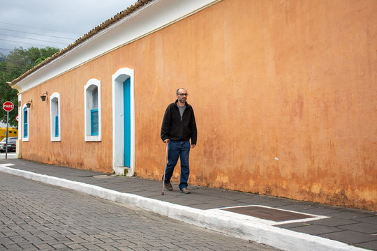 Disabled man walks with walking stick and difficulty on the street