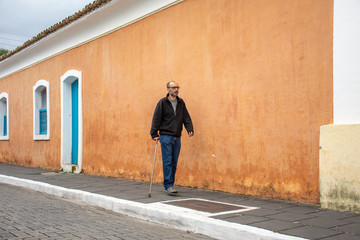 Disabled man walks with walking stick and difficulty on the street