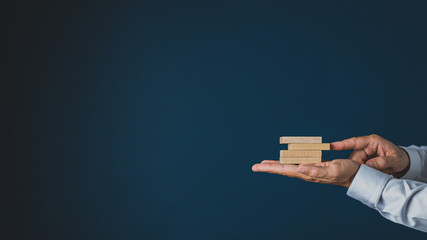 Businessman stacking wooden pegs