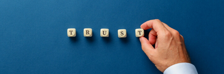 Businessman assembling the word trust with wooden dices