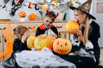 Family have funny time at home. Mother and daughter going to bite a pumpkin -Halloween concept