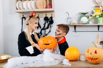 Mother and son holding a pumpkin during preparations to Halloween.
