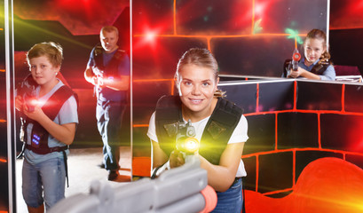 Excited girl aiming laser gun near other players during laser ta