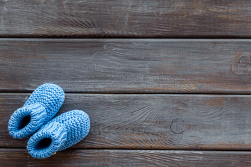 Fototapeta na wymiar Knitted blue footwear for baby on wooden background top view mockup
