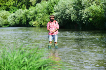 Fototapeta na wymiar Happy fisherman fishing in river holding fishing rods. Trout on a hook. Fish on the hook. Man with fishing rods on river berth. Angler.