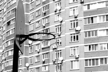 Basketball ring isolated with metal mesh at house background. Urban view. Monochrome photo. Black and white image. Sport concept 