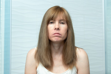 Woman with long hair looking sick and tired in the bathroom