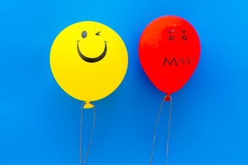 Obraz na płótnie Canvas Treat depression concept. Balloons with frustrated and smiling faces on blue background top view