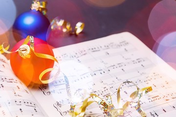 Fototapeta na wymiar Christmas tree colorful toys with music book close-up in sunlight
