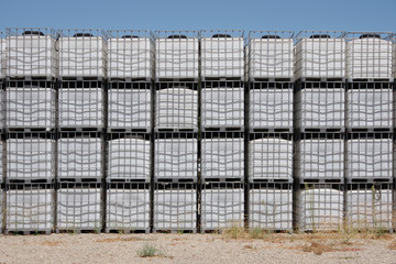 A section of a large wall of large container tanks for wine stacked outside of a production facility in the Santa Barbara wine region at harvest time