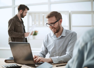 smiling businessman uses a laptop to work on a new project