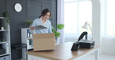 Businesswoman unboxing belongings and sitting to work on laptop at her new office - Powered by Adobe