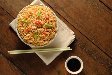 Instant noodles in a bowl with a cloth placed on a wooden table,chopsticks placed beside,topview,copy space