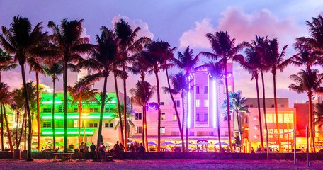 Miami Beach Ocean Drive hotels and restaurants at sunset. City skyline with palm trees at night. Art deco nightlife on South beach