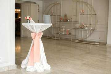 Concierge table for a wedding ceremony, decorated with pink fabric. Holiday Decor