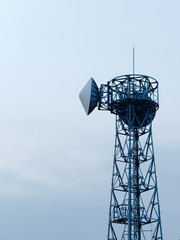Microwave antenna tower for radio communications against cloudy sky.