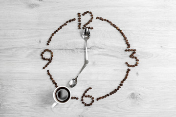 Coffee grains folded in the form of a clock on a wooden background. Instead of the number 7, a cup...