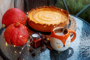 A cozy autumn dinner on the balcony. Pumpkin pie and hot cocoa in a cute orange fox-shaped mug. Cozy autumn.