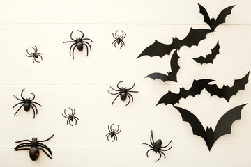 Halloween background with paper bats, spiders on white wooden background. Halloween holiday decorations. Flat lay, top view, copy space. Party invitation mockup, celebration.