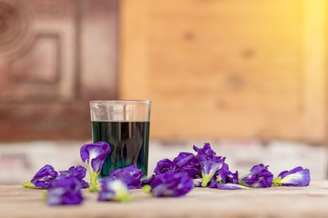 Butterfly pea flower cup with wooden wall blur.