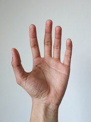 a man show hand five fingers on white wall background.