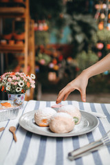 human pick homemade bun with powdered sugar. Sweet breakfast.Close up view of baker is working.Tasty sweet buns with sweetened condensed milk, Thai tea custard on plate and icing sugar