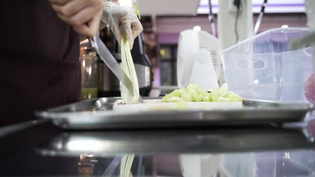 Hands cutting celery plant into small pieces for making juice