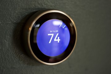 Isolated smart home thermostat on blue wall up close macro in cooling room