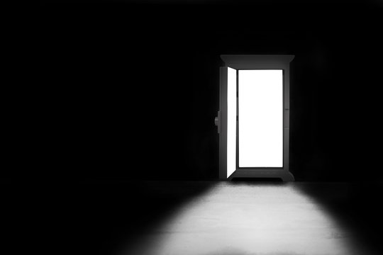 Abstract image of Light shining through opened door in dark room.